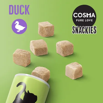 COSMA PURE LOVE SNACKIES DUCK. Billede af frysetørrede ternede snacks og dåse med sort kat på grøn baggrund. Synligt tekst: DUCK, COSMA PURE LOVE SNACKIES.