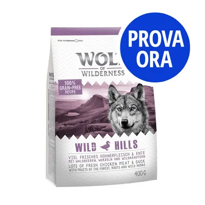 Confezione Wolf of Wilderness Wild Hills 400 g, ricetta senza cereali, pollo e anatra, scritta 'PROVA ORA' su cerchio blu. Testo in inglese e tedesco visibile sulla confezione.