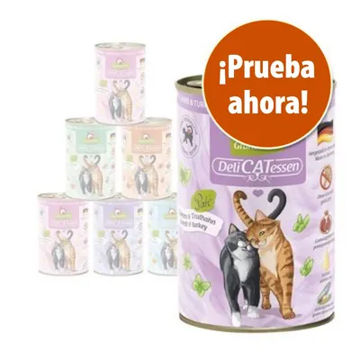 Lata de comida para gatos DeliCATessen con ilustración de dos gatos y texto destacado: ¡Prueba ahora! Varias latas apiladas al fondo, diferentes colores visibles en el envase.