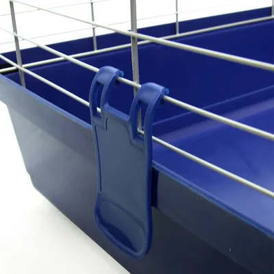 Détail d’une cage pour petits animaux avec bac en plastique bleu et grille métallique, fixation en plastique visible sur le côté.