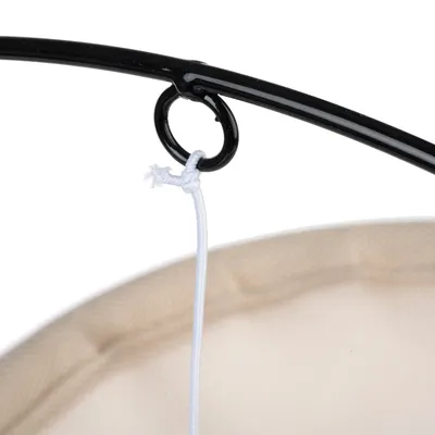 Primer plano de un anillo de metal negro con cuerda blanca, sujeto a un material de red beige.