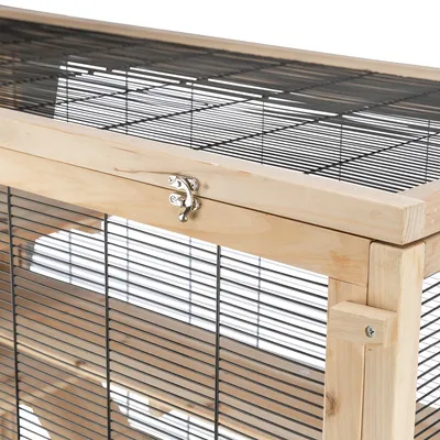 Détail d’une cage en bois et métal avec grille noire, cadre en bois clair et loquet métallique visible sur la porte supérieure.