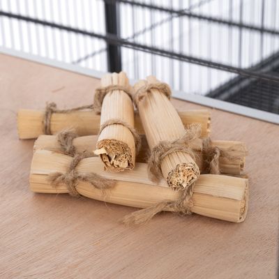 Kilka wiązek z naturalnego drewna, związanych sznurkiem jutowym, na drewnianej powierzchni przed metalową kratą.