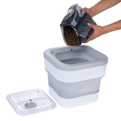 Recipient pentru hrană cu capac detașabil, culori gri și alb. Mâini toarnă hrană uscată dintr-o pungă în recipient.