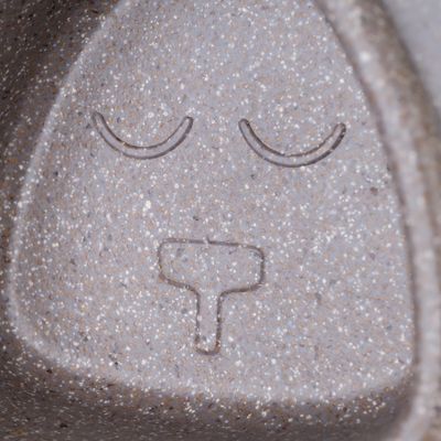 Primo piano di una superficie grigia con simbolo inciso: due occhi chiusi e un naso a forma di T.