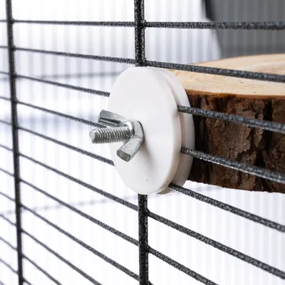 Detailaufnahme einer Holzplattform, die mit einer Flügelschraube und Kunststoffscheibe an einem Metallgitter befestigt ist.