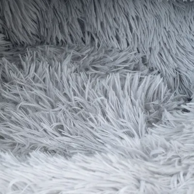 Prim-plan cu material gri, pufos, cu fibre lungi, posibil potrivit pentru paturi sau pături pentru animale de companie.