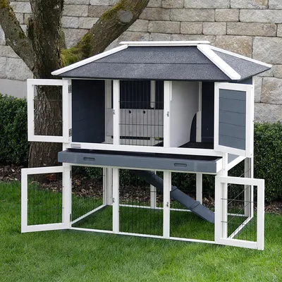 Clapier à deux niveaux en bois et grillage, toit gris, portes ouvertes, rampe intérieure visible, tiroir coulissant sous l’étage supérieur. Installé sur pelouse extérieure.