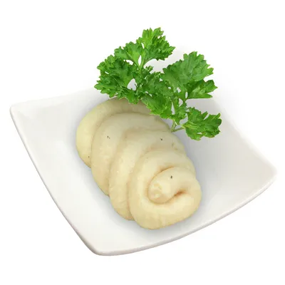 Purée beige en spirale servie dans une assiette carrée blanche, garnie d'une branche de persil frais. Aucun emballage ou marque visible.