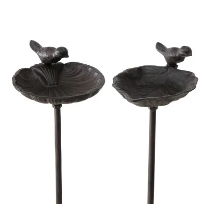 Zwei braune Vogeltränken aus Metall mit dekorativen Vogelfiguren auf Ständern. Zwei braune Vogeltränken aus Metall mit dekorativen Vogelfiguren auf Ständern.