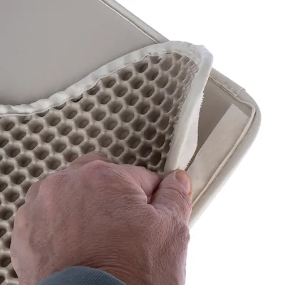 Mano che mostra la fodera rimovibile con struttura a nido d'ape e chiusura in velcro su un tappetino per animali.