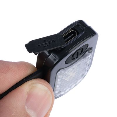 Nahaufnahme eines USB-Ladeanschlusses an einem schwarzen Gerät mit Schutzkappe, gehalten von einer Hand.