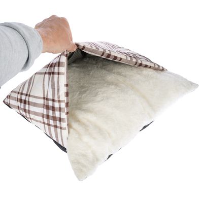 Hand öffnet ein Kissen mit braun-weiss kariertem Bezug und weicher, weisser Plüschfüllung.