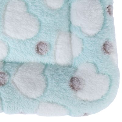 Tapis ou coussin en tissu peluche bleu clair avec motifs de nuages blancs et pois gris visibles sur la surface.