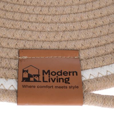 Modern Living Where comfort meets style (texte en anglais) sur une étiquette en simili cuir cousue sur un tressage beige, logo avec deux animaux stylisés dans une maison.