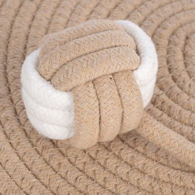 Zabawka węzeł z beżowo-białego, plecionego i wytrzymałego sznura. Zbliżenie węzła na pasującym podkładzie z liny.