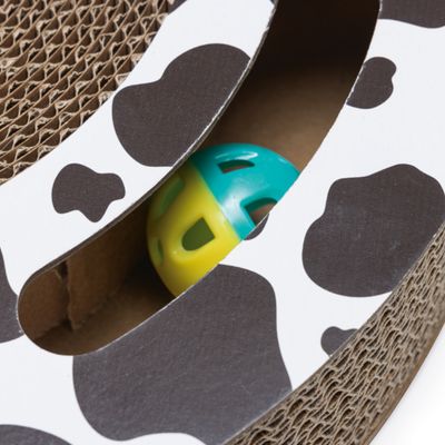 Speelbal in geel en blauw, ingebed in een krabplank van golfkarton met koeienprint.