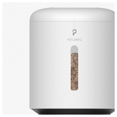 Distributeur automatique blanc PETLIBRO avec réservoir transparent partiellement rempli de croquettes visibles à l’avant. Marque PETLIBRO inscrite sur le dessus du réservoir.