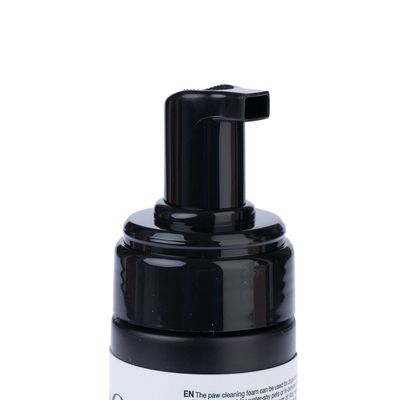 Zwarte pompdispenser van een pootreinigingsschuimfles, tekst op de fles deels zichtbaar: 'EN The paw cleaning foam can be used for...'.