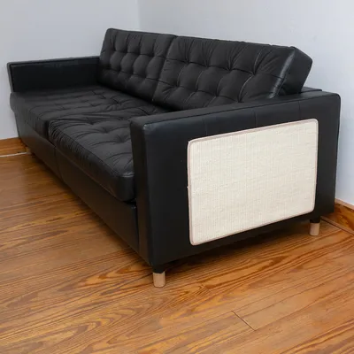 Sofá de cuero negro con protección lateral de sisal claro, adecuado para el cuidado de las garras de los gatos. Sofá de cuero negro con protección lateral de sisal claro, adecuado para el cuidado de las garras de los gatos.