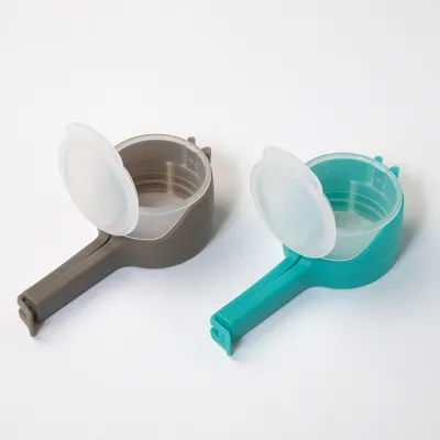 Two measuring cups with lids, one grey and one turquoise, made of plastic. Suitable for precise measuring of pet food.