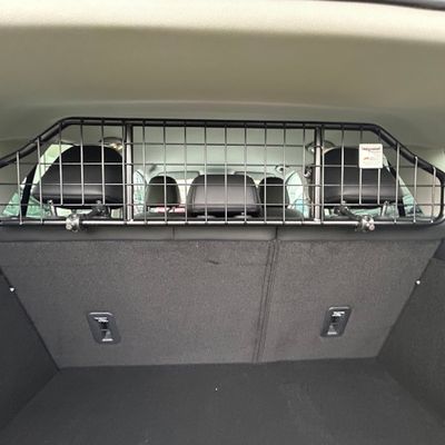 Griglia divisoria in metallo per auto, nera, montata tra bagagliaio e sedili posteriori. Visibili: poggiatesta dei sedili ed elementi di fissaggio della griglia.