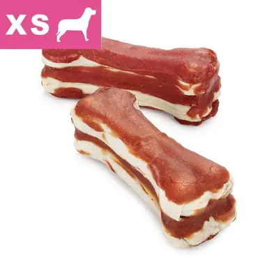 Przysmak w kształcie kości, dwukolorowy, rozmiar XS widoczny na różowym tle z sylwetką psa. Widoczne trzy sztuki produktu.