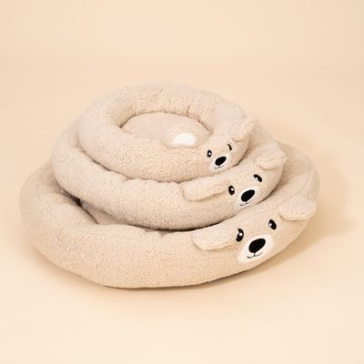 Drei runde, beige Kuschelbetten mit Bärengesicht und Ohren, übereinander gestapelt. Weiches Material sichtbar.