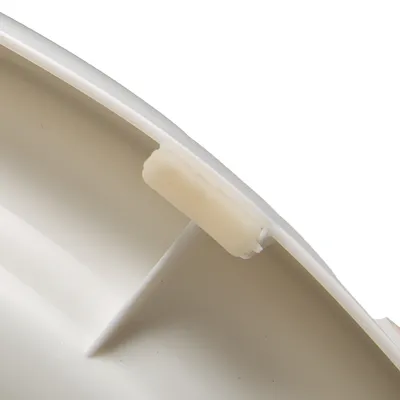 Detailní záběr na bílý plastový díl s malým držákem nebo klipem na okraji.