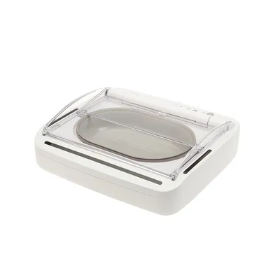 Valkoinen automaattinen ruokinta-automaatti, jossa läpinäkyvä kansi ja soikea ruokakuppi. Näkyvät ohjauspainikkeet ylhäällä. Valkoinen automaattinen ruokinta-automaatti, jossa läpinäkyvä kansi ja soikea ruokakuppi. Näkyvät ohjauspainikkeet ylhäällä.