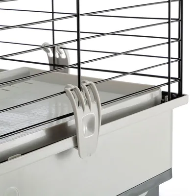 Détail d’une cage pour petits animaux avec structure en métal noir et bac en plastique gris, fixation latérale visible sur le bord du bac.