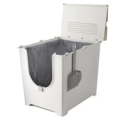 Caja de arena blanca de plástico con tapa abierta, forro interior gris y pala recogedora colgada en el lateral.