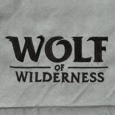 Wolf of Wilderness. Nome del marchio su tessuto grigio.