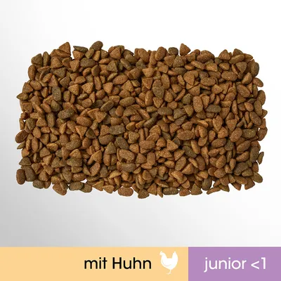 Suché krmivo, text: mit Huhn, junior <1. Granule různých tvarů, barva hnědá. Text v němčině na spodním okraji obrázku.