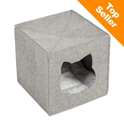 Grå kubformad kattbädd i filt med öppning formad som ett katthuvud och vit kudde inuti. Orange hörn med texten 'Top Seller' uppe till höger.