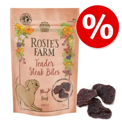 Rosie's Farm Tender Steak Bites Beef, 70 g, prigrizki za odrasle pse. Na embalaži je simbol brez žit in velik rdeč znak za popust (%). Prikazani so tudi trije koščki prigrizka. Rosie's Farm Tender Steak Bites Beef, 70 g, prigrizki za odrasle pse. Na embalaži je simbol brez žit in velik rdeč znak za popust (%). Prikazani so tudi trije koščki prigrizka.