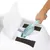 Pelle en plastique turquoise utilisée pour nettoyer une litière pour chat blanche avec couvercle ouvert et filtres visibles.