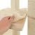 Mano levantando una funda acolchada beige de una plataforma de madera, parte de un rascador para gatos con postes de sisal visibles.