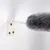 Grijs, pluizig object bevestigd op een witte wandhouder met drie schroeven. Grijs, pluizig object bevestigd op een witte wandhouder met drie schroeven.