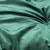 Close-up van een groene, fluweelachtige stof met zachte textuur en plooivorming.