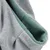 Close-up view of grey and green fabric material, possibly part of a product such as a bag or clothing.