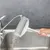Hand holding a lint roller with washable design under running water at the sink. Shows easy cleaning of the roller.