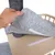 Hand showing grey felt pad with hook-and-loop fastener on wooden platform, suitable for attachment to scratching post.