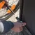 Montage eines Fahrradanhängers: Hand befestigt Metallstange am Rahmen neben einem Rad mit orangefarbenem Reflektor.