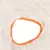 Detailansicht eines weissen, flauschigen Materials mit orangefarbenem Rand und einer ovalen Öffnung.