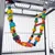Échelle suspendue en bois multicolore avec perles et barreaux, accrochée à l’intérieur d’une cage métallique pour oiseaux. Formes variées visibles sur les éléments en bois.