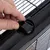 Close-up of a black locking mechanism on a wire cage being opened by a hand.