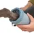 Patte de chien insérée dans un gobelet bleu muni de brosses internes, tenue par une main humaine. Produit en plastique visible, sans marque apparente.