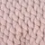 Gros plan sur une maille épaisse en tissu doux de couleur rose pâle, aspect tricoté. Matériau visible : textile.