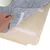 Hand lifts grey felt mat with hook-and-loop fastener from a wooden board. Roll of white rope visible in the background.